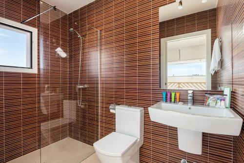 een badkamer met een toilet, een wastafel en een spiegel bij Villa Galerna in Son Bou