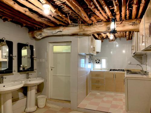 a bathroom with two sinks and a wooden ceiling at بيت القرية التراثية in Tanomah