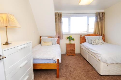 a bedroom with two beds and a window at Whitby Spacious Rugby Field Cottage with off-street parking and EV fast point for electric cars in Whitby
