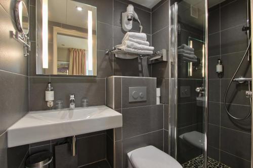 une salle de bain avec un lavabo et une douche dans l'établissement Villa Margaux Opéra Montmartre, à Paris