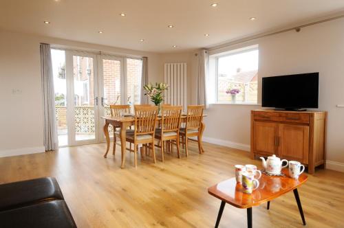 a living room with a table and a television at Whitby Spacious Rugby Field Cottage with off-street parking and EV fast point for electric cars in Whitby