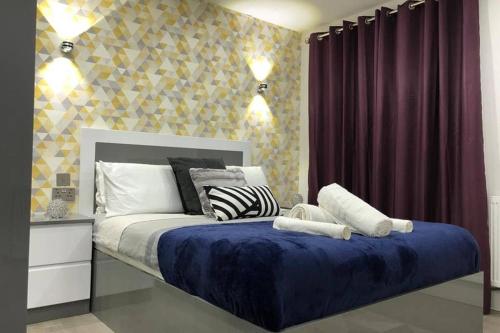 um quarto com uma cama grande e um cobertor azul em Morden Central Self Contained Flat by CozyNest em Reading