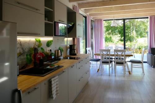 une cuisine avec des placards blancs et une salle à manger avec une table dans l'établissement Ulinia Zacisze Dom Superior 90m2, à Ulinia