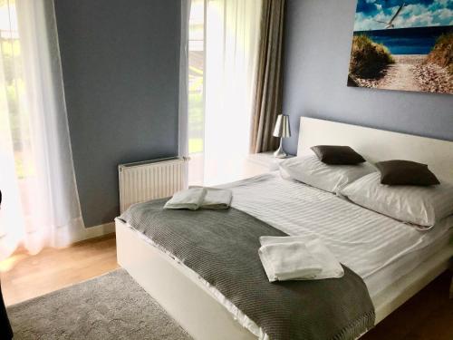 a bedroom with a white bed with a blue wall at Apartament Family Beach przy Golden Tulip in Międzyzdroje