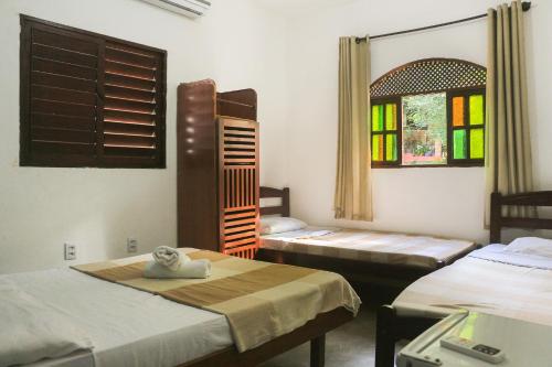 una camera con due letti e una finestra di Hospedaria Flor de Caju a Pipa