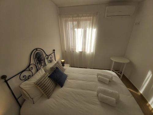 um quarto branco com uma grande cama branca com almofadas em Sun and Beach II AC Wifi 90mts from the Beach em Portimão