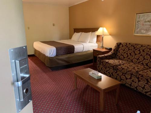 a hotel room with a bed and a couch at Red Carpet Inn & Suites Ebensburg in Ebensburg