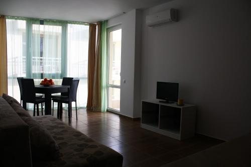 a living room with a television and a table with chairs at Guest House ASK in Primorsko