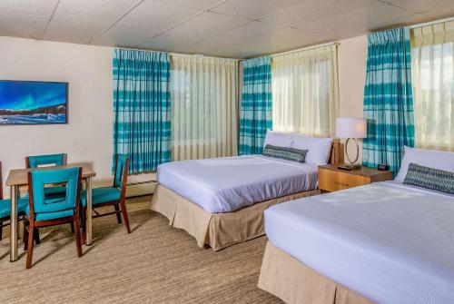 a hotel room with two beds and a table and chairs at Bridgewater Hotel, Trademark Collection by Wyndham in Fairbanks