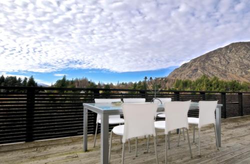 a table and chairs on a deck with a view at Treehouse Spa Escape - Private Spa Pool in Queenstown