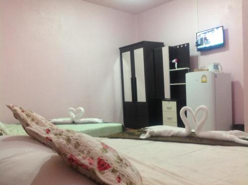 a bedroom with a bed with a pillow and a refrigerator at Ruan Mai Naiyang Beach Resort in Nai Yang Beach