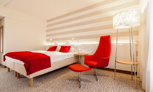 a hotel room with a bed and a red chair at Radisson Blu Hotel Karlsruhe in Ettlingen