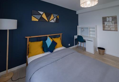 1 dormitorio con 1 cama con paredes azules y escritorio en Appartement 3 chambres - Parking - Wifi - Buanderie - Jardin, en Brest