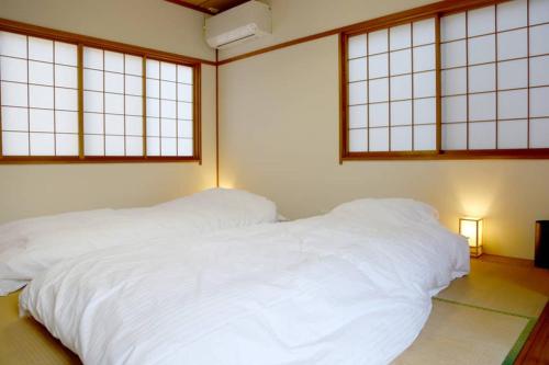 a bedroom with a large white bed with windows at Tsukuyomi Chuodori in Kanazawa
