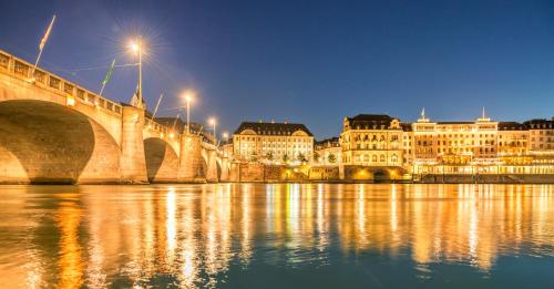 a bridge over a river with buildings and lights at Essential by Dorint Basel City in Basel