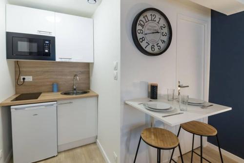 une cuisine avec une petite table et une horloge murale dans l'établissement Studio Cosy - Parking - Wifi - Buanderie - Jardin, à Brest