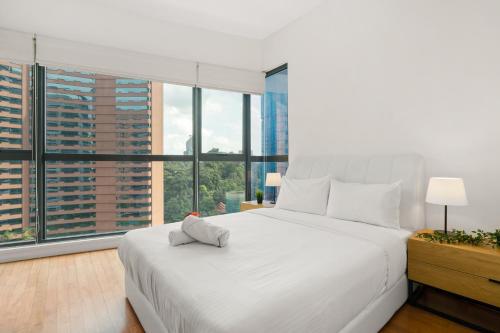 a bedroom with a large white bed and large windows at Cendana by Plush in Kuala Lumpur