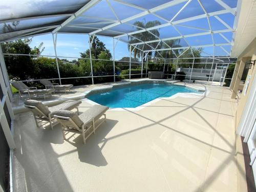 a patio with a pool and chairs and an umbrella at Mickeys Pearl - Phenomenal 7BR with 4 Master Suites Privacy Pool & Hot Tub Gas BBQ - 2 miles to Disney in Orlando
