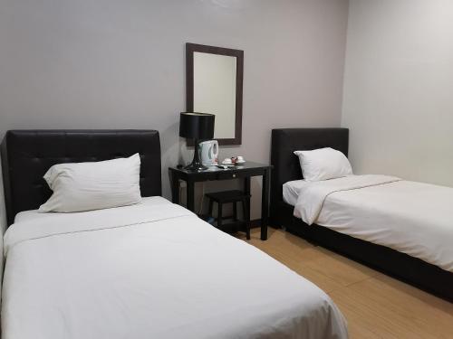 a bedroom with two beds and a table with a mirror at Fargo Boutique Hotel in Kuantan