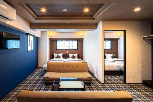 a room with two beds and a couch and a mirror at Stay SAKURA Tokyo ASAKUSA ART DECO HOTEL in Tokyo
