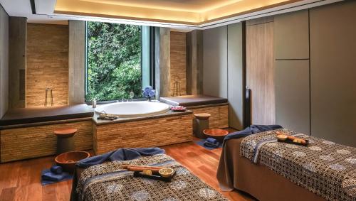 a bathroom with two beds and a bath tub at Royal Tulip Gunung Geulis Resort and Golf in Bogor