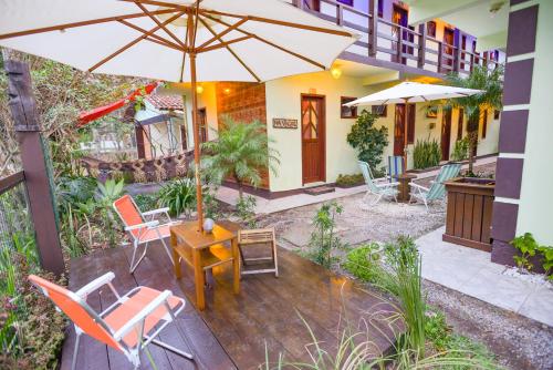 a patio with a table and chairs and an umbrella at Pousada Bem te vi in Garopaba
