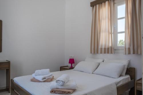 a bedroom with a white bed with towels on it at Paradise Apartments Studios in Mylopotas