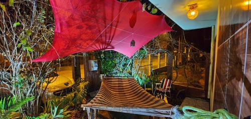 a tree sitting on a bench with a red umbrella at Pousada Bem te vi in Garopaba