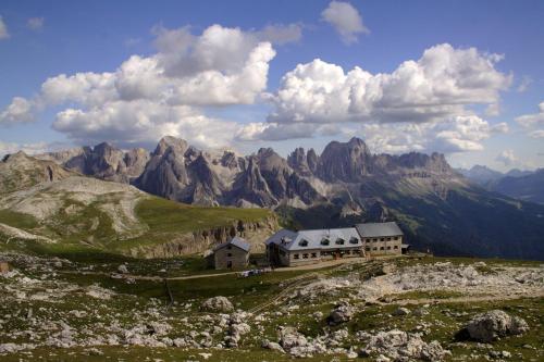 a building on a hill with mountains in the background at Hotel Piné in Tires