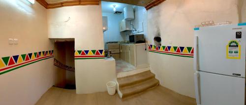 a kitchen with a refrigerator and stairs in a room at بيت القرية التراثية in Tanomah