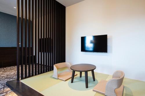 a room with two chairs and a table and a tv at Wires Hotel Shinagawa Seaside in Tokyo
