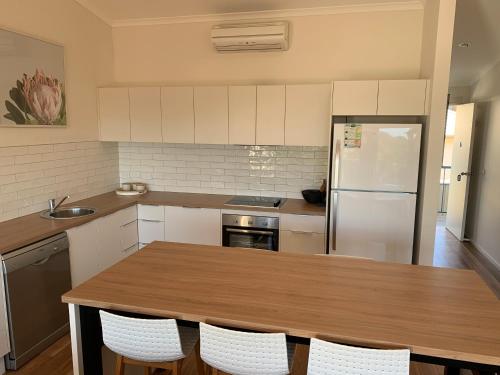 a kitchen with a wooden table and a refrigerator at BlueWater Apartments in Merimbula