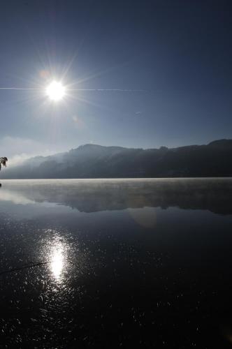 a large body of water with the sun in the sky at Pension Paßler in Seeboden