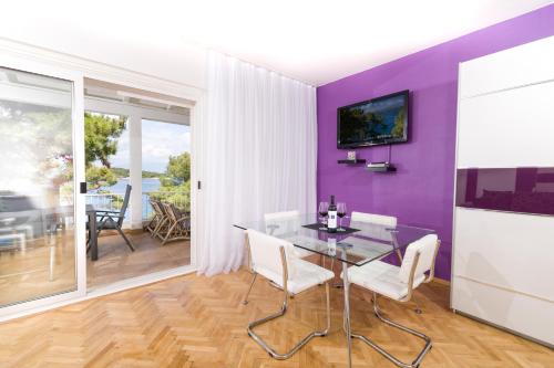 jadalnia ze szklanym stołem i fioletową ścianą w obiekcie Apartments Dobronic w mieście Jelsa