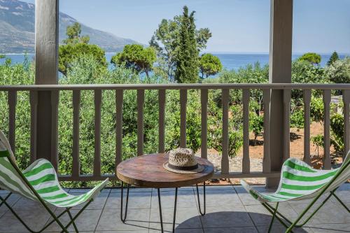 a table and chairs on a porch with a view of the ocean at Ploes Luxury Cottages in Kefallonia