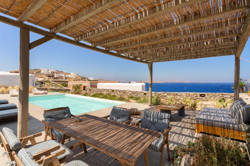 a patio with a wooden table and chairs and a pool at Nikoi Villas in Mikonos