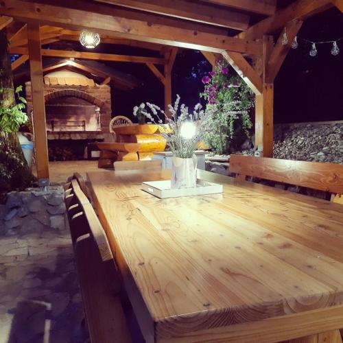 a wooden table with a vase of flowers on a patio at Kuća za odmor Bitoševje in Klenovnik