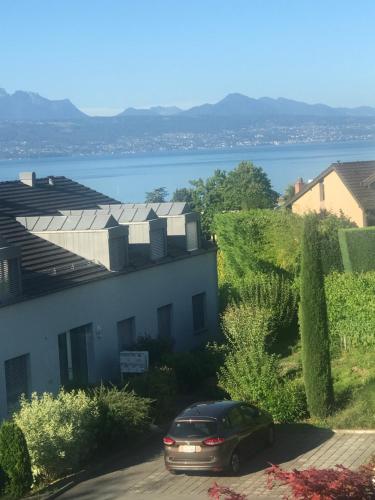 a car parked next to a house with a view of the water at La maison du lac in Lutry