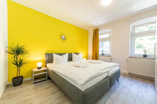 a bedroom with a large bed with a yellow wall at Haus am Malerweg in Bad Schandau