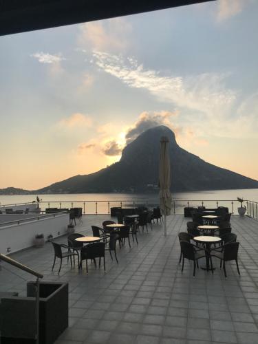 a deck with tables and chairs and a mountain at MASSOURI BEACH HOTEL in Masouri