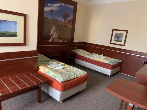 a room with two beds and a table at Penzion Mánes in Krabčice