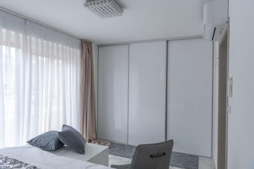 a bedroom with a bed and a chair next to a window at Apartments Petra Krk in Krk