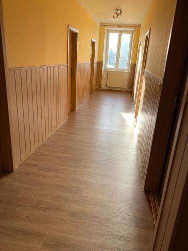 an empty hallway with a wooden floor and a window at Penzion Mánes in Krabčice