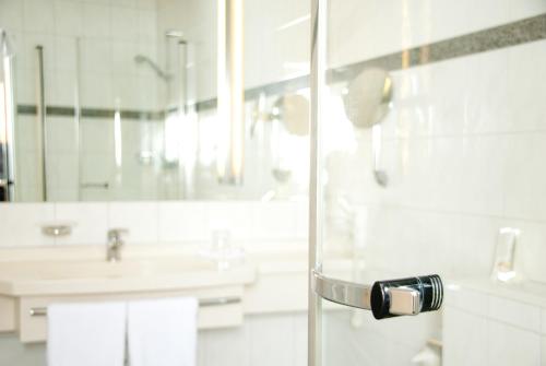 ein Bad mit einer Glastür mit einem Waschbecken in der Unterkunft Etzhorner Krug in Oldenburg