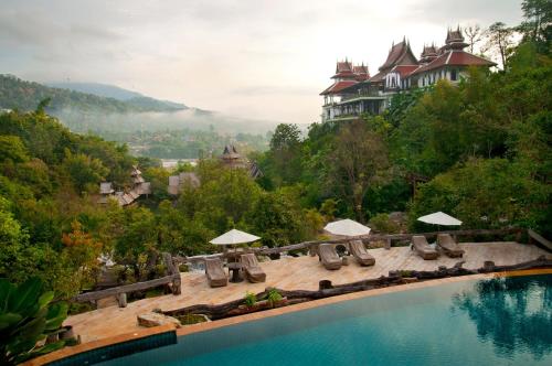un complejo con una piscina con sillas y sombrillas en Panviman Chiang Mai Spa Resort en Mae Rim