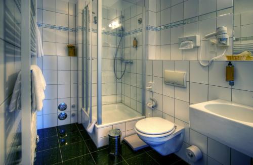 a bathroom with a toilet and a shower and a sink at KurparkHotel Warnemünde in Warnemünde