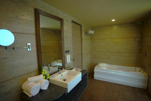 a bathroom with a sink and a tub and a mirror at Renest Gandhidham in Gandhidham