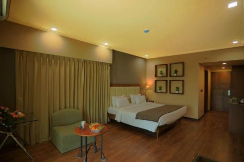 Großes Hotelzimmer mit einem Bett und einem Tisch in der Unterkunft Renest Gandhidham in Gandhidham