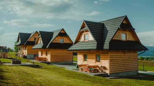 a row of wooden houses with black roofs at Domki Szarotki in Groń