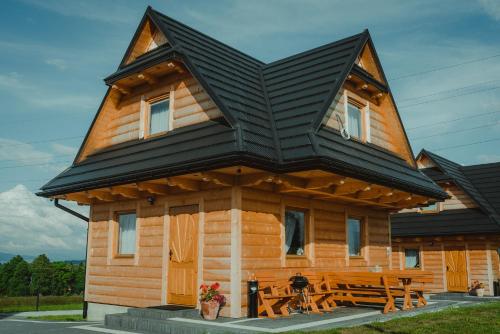 a wooden cabin with a table in front of it at Domki Szarotki in Groń